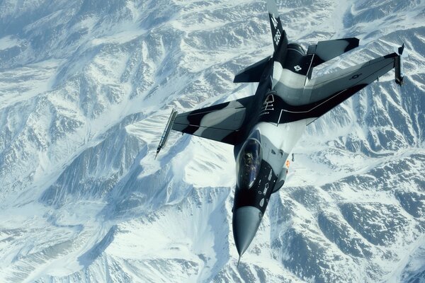 On the snow-white background of the mountains, the flight of a fighter is visible