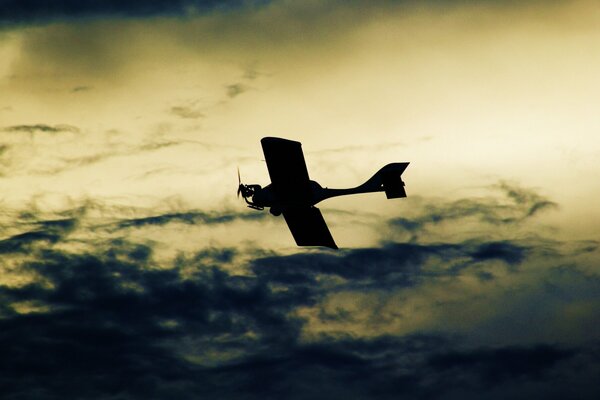 Dunkles Flugzeug fliegt vor dem Hintergrund dunkler Wolken