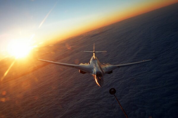 Refueling of a fighter in flight against the background of sunset