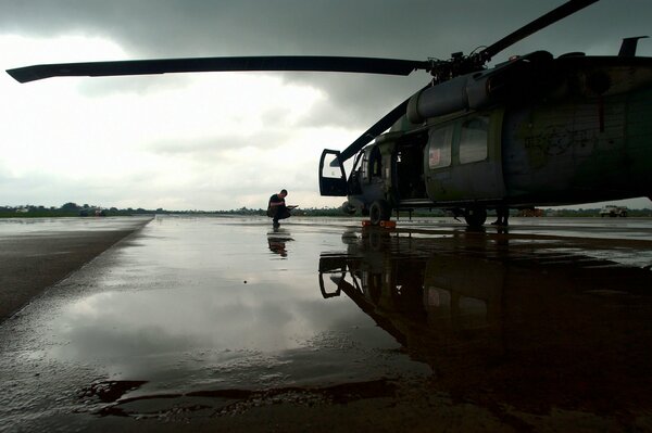 The helicopter is on the field after the rain