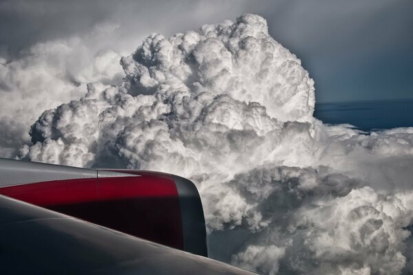 Der Flügel des Flugzeugs ist vor dem Hintergrund der harten Wolken sichtbar