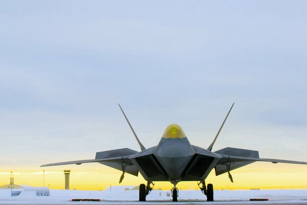 Chasseur Raptor se trouve sur l aérodrome sur fond de coucher de soleil