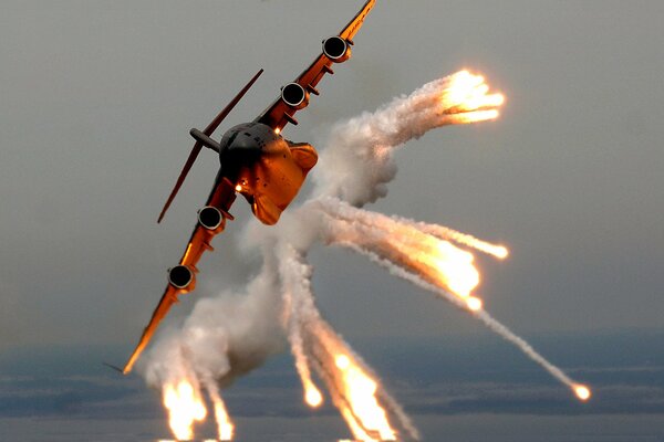 Огромный летящий в небе самолёт выпускает огонь и дым