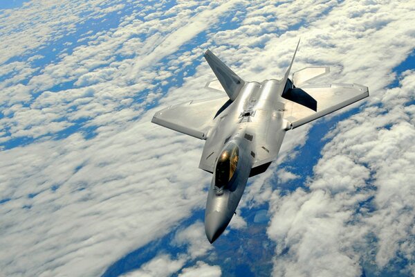 Above the clouds of high altitude, the flight of a fighter is visible