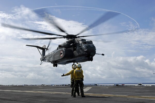 Two people are directing the helicopter landing on the runway