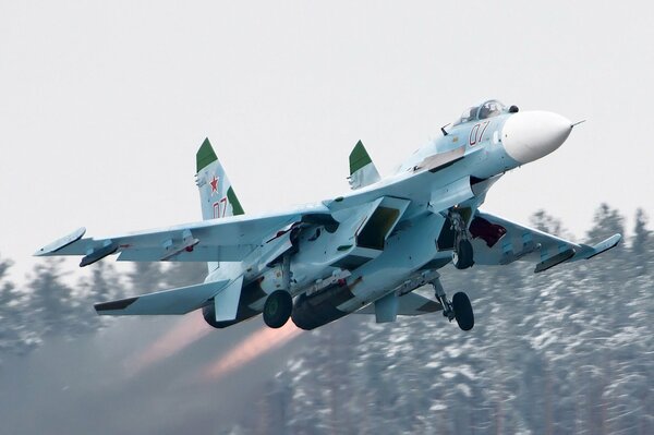 Start myśliwca Su-27 na tle drzew