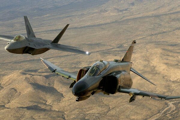 Avions de chasse américains puissants f-22raptor et f-4phantom2 dans le ciel sur fond de terre