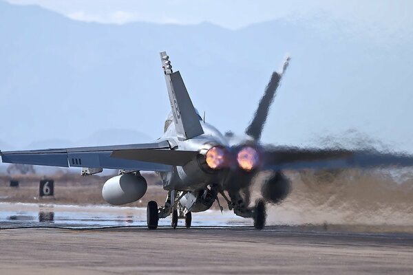 A fighter jet on the runway . Rear view