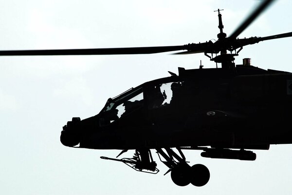 Silhouette of a flying helicopter with a machine gun