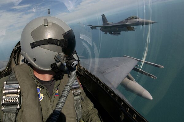 Un pilota militare osserva dalla cabina di pilotaggio un aereo che vola nelle vicinanze