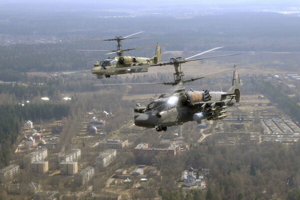 Dwa śmigłowce Ka-52 na niebie nad miastem