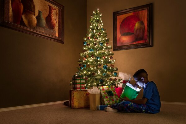 Niño con regalos en el árbol de Navidad