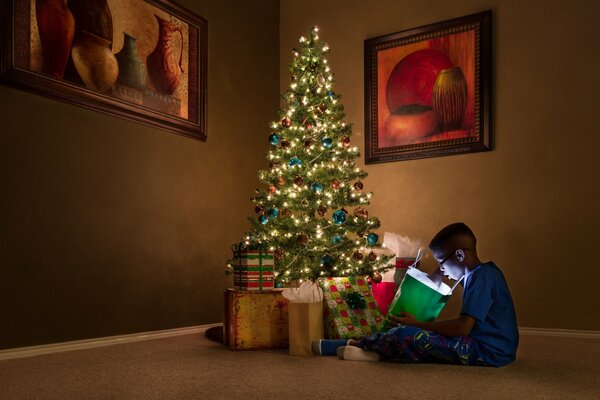 Garçon avec des cadeaux à l arbre de Noël
