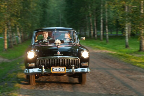 La novia y el novio van a la boda en un coche retro