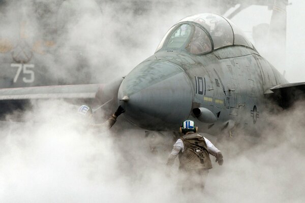 A man in smoke in front of an aircraft carrier fighter