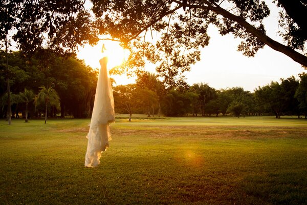Auf dem Hintergrund des Sonnenuntergangs weißes Kleid