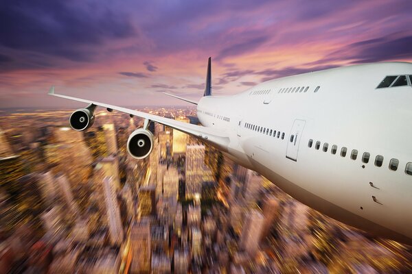 Airplane flight over the city at sunset