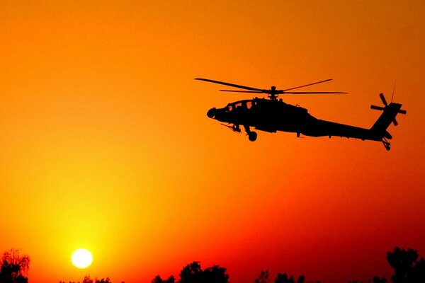 Silhouette eines fliegenden Hubschraubers bei Sonnenuntergang