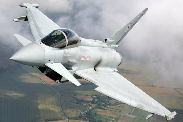 Avión de combate volando en las nubes sobre la tierra