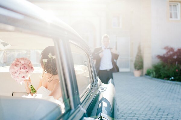 Mariée avec un bouquet dans la voiture