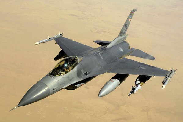 Un F-16 a bordo vola attraverso il cielo sopra il deserto