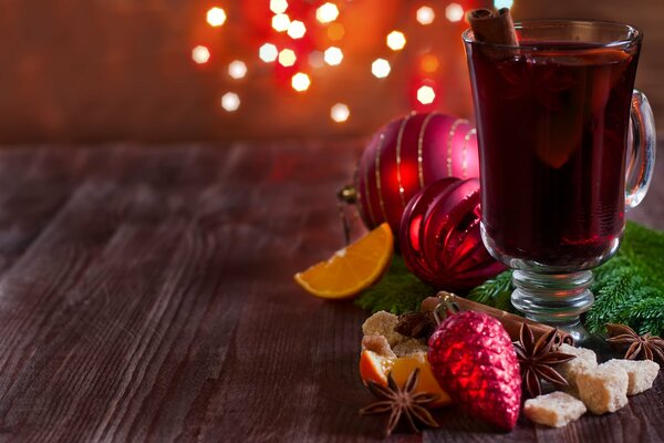 Mug with mulled wine on the table with spices and Christmas toys