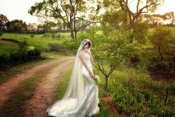 Fille en robe de mariée sur la route dans la forêt