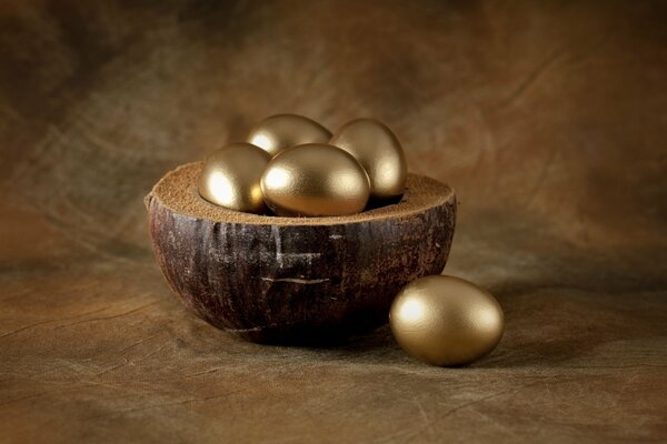 Huevos de Pascua dorados en un recipiente de madera