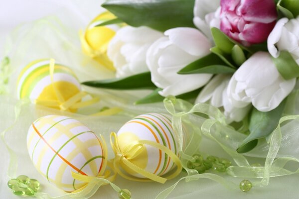 Easter eggs on the table with ribbons and flowers