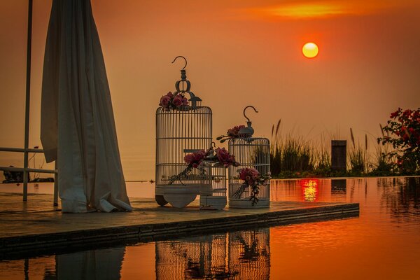 Jaulas blancas para pájaros en el fondo de la puesta de sol