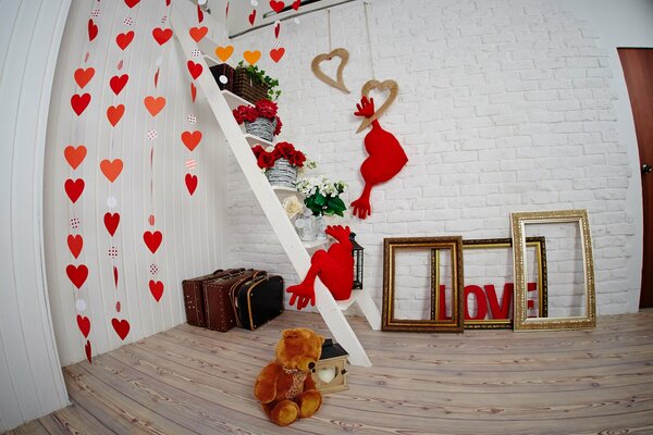 Studio photo décoré pour la Saint-Valentin avec des coeurs muraux, des cadres, des oreillers et un ours