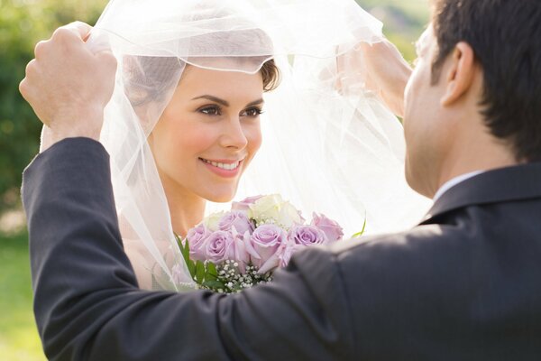 Wedding photo of the groom lifting the veil to the bride