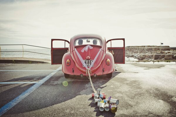 An old-style car, aluminum cans are tied to it