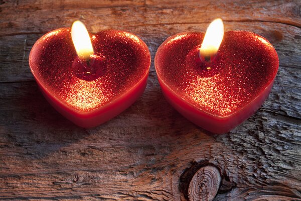 Due candele rosse a forma di cuore che bruciano