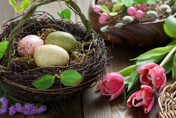 Huevos de Pascua en una canasta y tulipanes rosados