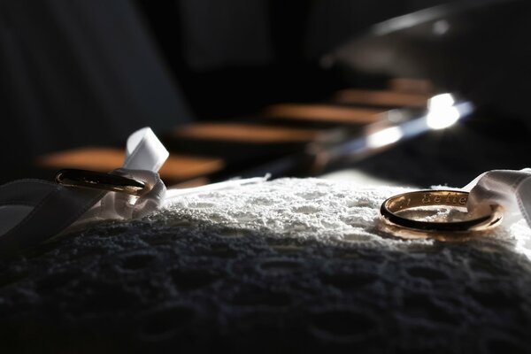 Dos anillos de boda en cintas blancas