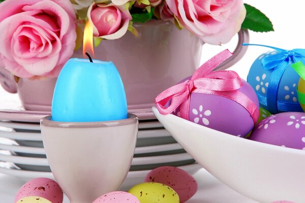 Table setting in pastel colors, Easter eggs, a bouquet of pink roses, a lit candle