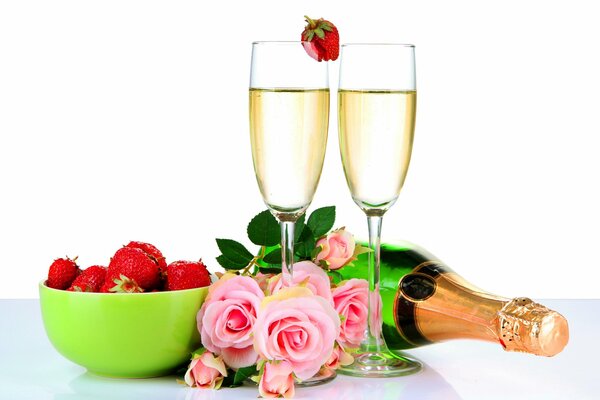 Glasses filled with champagne, delicious strawberries and a fragrant bouquet of roses