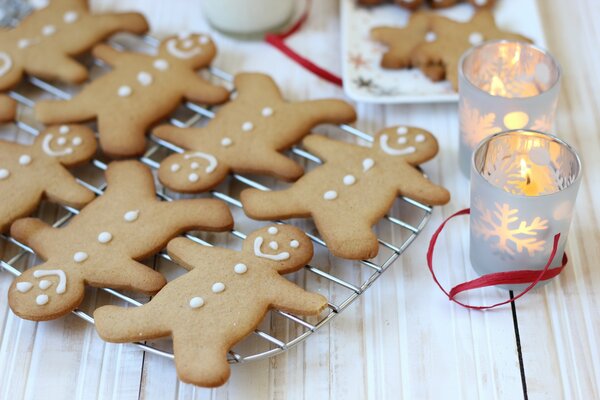 Pan di zenzero festivo di Capodanno e Natale a forma di omini con una faccia sorridente e una candela accesa in un portacandele