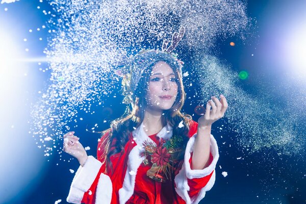 Asian woman with horns in Santa Claus costume throws shiny dust