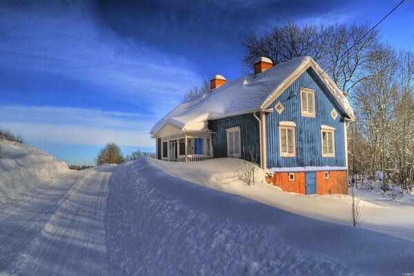 Blue country house in winter. Snow on the roof