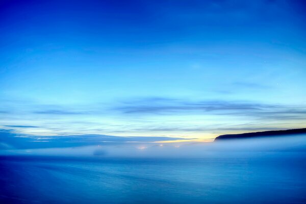 Fog over the sea coast and the sky in the clouds