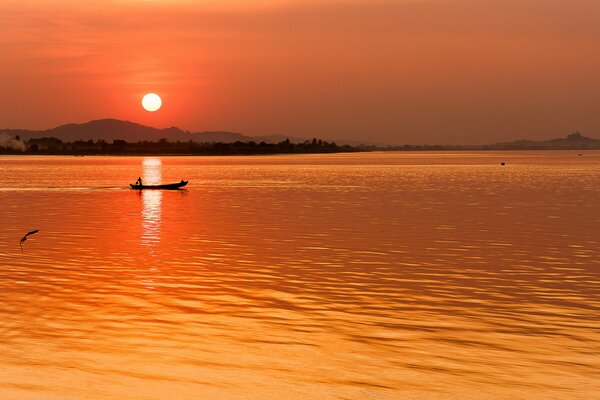 The boat sails on the lake at sunset