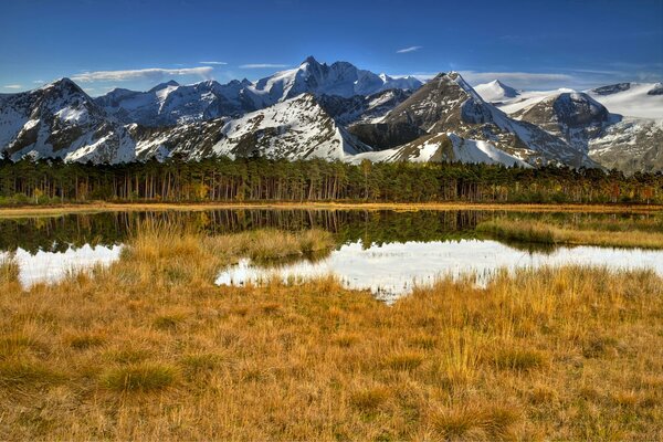 Schneebedeckte Berge am See im Herbst