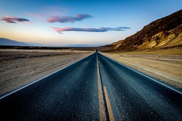 Sunset road in the desert with mountains