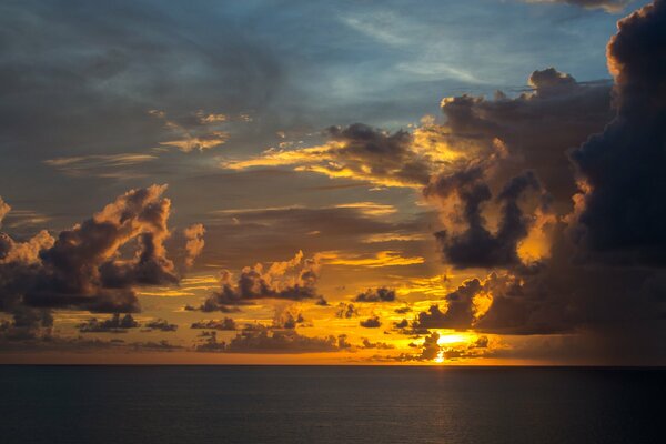 Puesta de sol en el mar. Las nubes encantadoras y el horizonte