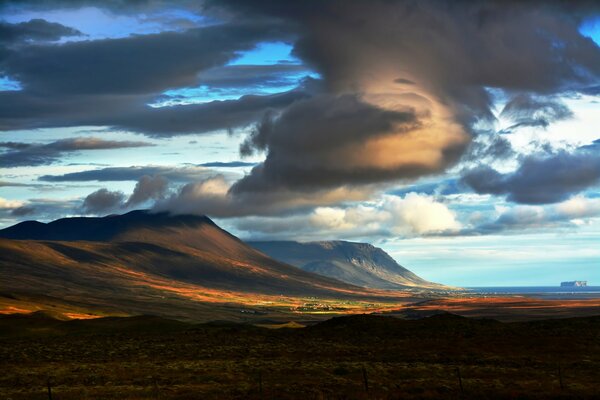 Des champs sans fin avec des montagnes et d énormes nuages