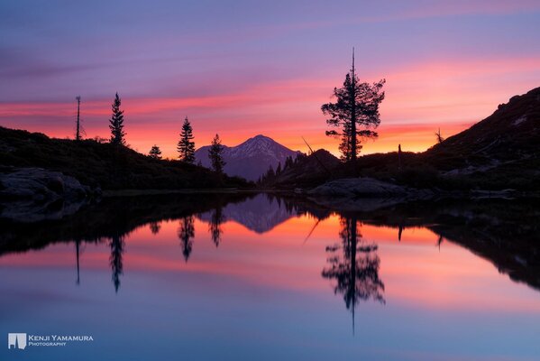 Brillante puesta de sol sobre un tranquilo lago de montaña