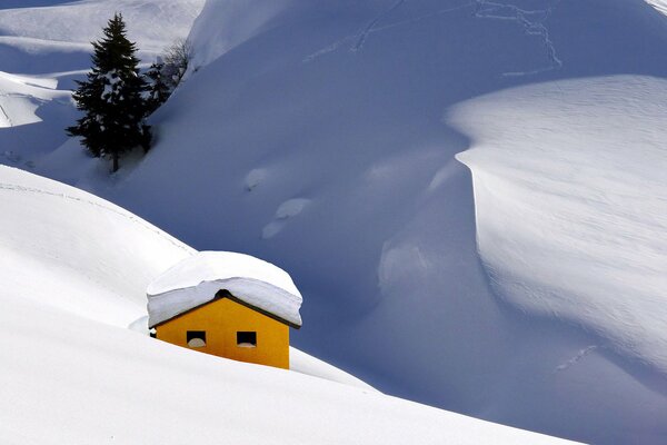 Maison de couleur jaune sur fond de montagnes enneigées