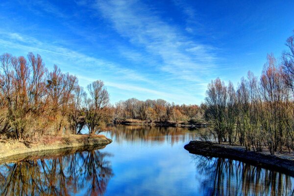 Reflexion im Wasser von Bäumen und Wolken